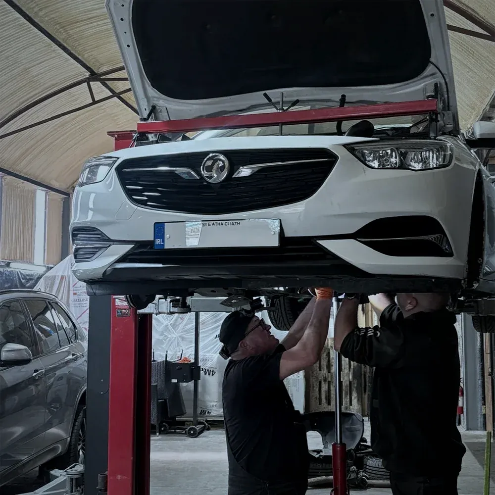 Two Alan Dawson Autoworks mechanics working underneath a car on the lift in the Navan workshop